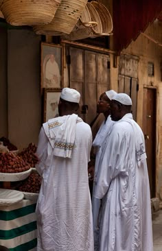 two men standing next to each other in front of a fruit stand