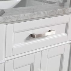 a white bathroom vanity with marble counter tops and drawers on each side, along with a sink