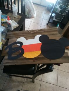 a mickey mouse cut out on top of a wooden table in a room with tile flooring