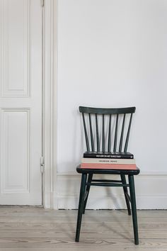 a black chair sitting in front of a white wall with a book on it's back