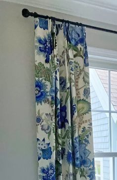 a curtain with blue flowers on it hanging in front of a window