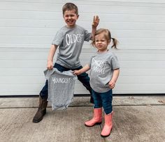 two young children wearing shirts that say curiosity and won't they? sitting on top of each other