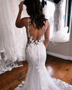 the back of a woman's wedding dress in front of a mirror