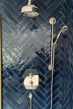 a shower head and hand held shower faucet in a blue tiled bathroom with gold accents