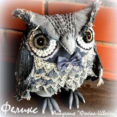 an owl statue sitting on top of a wooden table next to a brick wall,