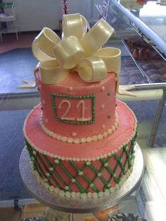 two tiered cake decorated with pink and green icing, gold bow and number 21