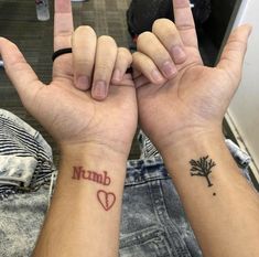 two people holding hands with tattoos on their wrists and the word love written in red ink