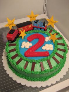 a birthday cake with a train on the top and two stars around it that says happy 2nd birthday