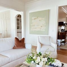 a living room filled with white furniture and flowers