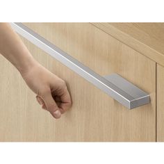 a person's hand is reaching for the door handle on a wooden cabinet drawer