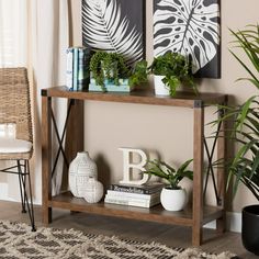 a wooden table topped with plants next to a wall mounted planter and two framed pictures