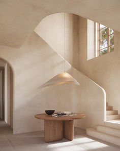 a round table in the middle of a room with stairs leading up to an open window