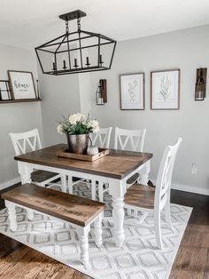 a dining room table with white chairs and a bench in front of it on top of a rug