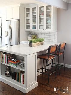 a kitchen with white cabinets and an island that has bookshelves on top of it