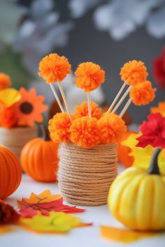 Craft project with orange pom-pom flowers in a twine-wrapped vase, surrounded by mini pumpkins and autumn leaves. Fall Crafts For Kids Easy, Projects For Toddlers, Fall Creations, Crafts For Kids Easy