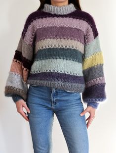 a woman wearing a multicolored sweater and jeans