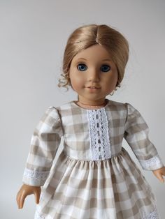 a doll with blonde hair wearing a white and brown checkered dress, blue eyes