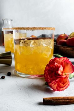 a glass filled with liquid next to an orange flower and cinnamon sticks on a table