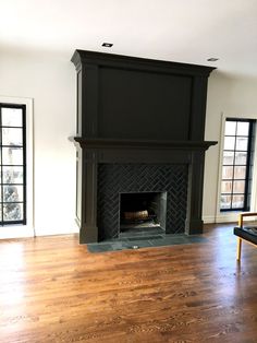 an empty living room with a fireplace and hard wood floors