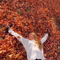 a woman laying on the ground surrounded by leaves