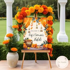 an orange and yellow wedding arch with flowers on the table next to it is welcome sign