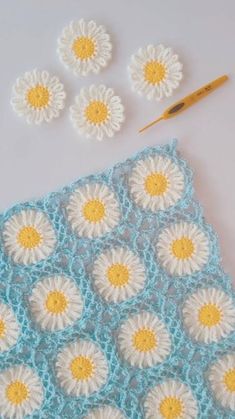 crochet flowers are laying on the table next to some knitting needles and yarn