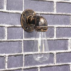 an old fashioned light bulb attached to a brick wall in front of a gray and white tiled wall