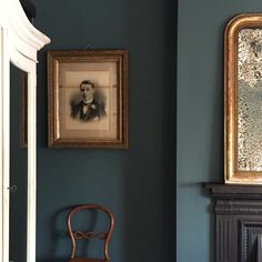 an old chair is sitting in front of two framed pictures on the wall above it