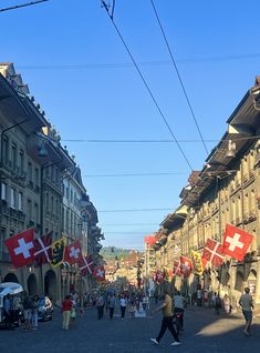 many people are walking down the street with flags in their hands and buildings behind them