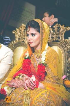 a woman sitting on top of a gold chair wearing a yellow and red wedding outfit