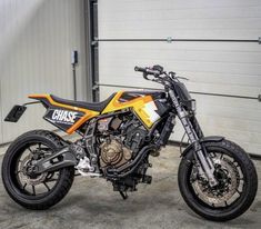 a yellow and black dirt bike parked in front of a garage door with it's wheels still on the ground