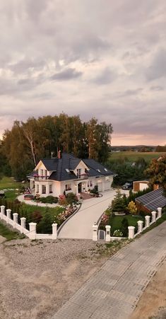 an aerial view of a large house surrounded by trees and shrubs, with a driveway leading to the front door