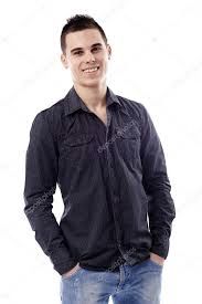 a young man standing with his hands in his pockets and smiling at the camera while wearing jeans and a black shirt