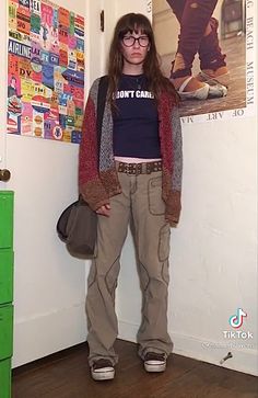 a woman standing in front of a wall with posters on it