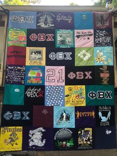 a large quilt made with various t - shirts on the side of a building in front of a tree