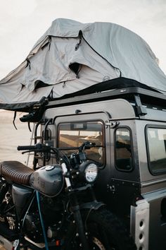 a motorcycle is parked next to a vehicle with a tarp on top of it