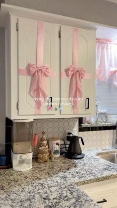 a kitchen with white cabinets and pink bows on the door handles that are tied to them