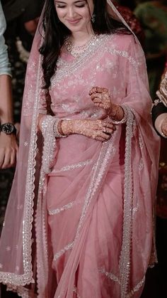 a woman wearing a pink sari and holding her hands together