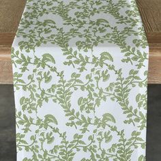 a green and white table runner sitting on top of a wooden table