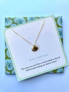 a card with a gold heart pendant on it and an inscription that says seas the day