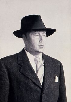 a man in a suit and hat poses for a photo