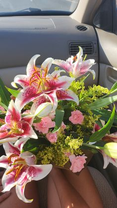 a bouquet of flowers sitting in the back seat of a car with someone's legs propped up