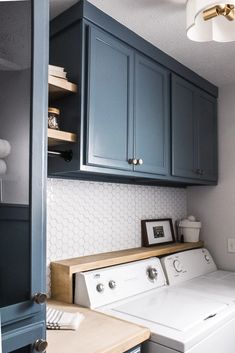 a washer and dryer in a room with blue cupboards on the wall