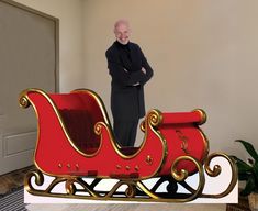 a man standing next to a red and gold sleigh