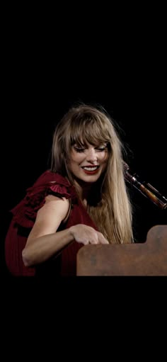 a woman with long blonde hair and red lipstick holding a pipe in her hand while sitting at a table