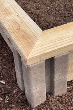 a bench made out of concrete blocks sitting in the dirt next to some mulch