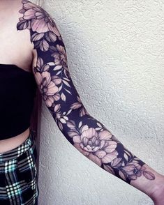 a woman's arm with flowers on it and a checkered skirt underneath her