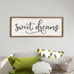 a wooden sign that says sweet dreams on the wall above a bed with green pillows