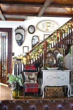 a living room filled with furniture and christmas decorations on the wall next to a stair case