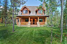 a log cabin sits in the middle of a grassy area surrounded by trees and grass